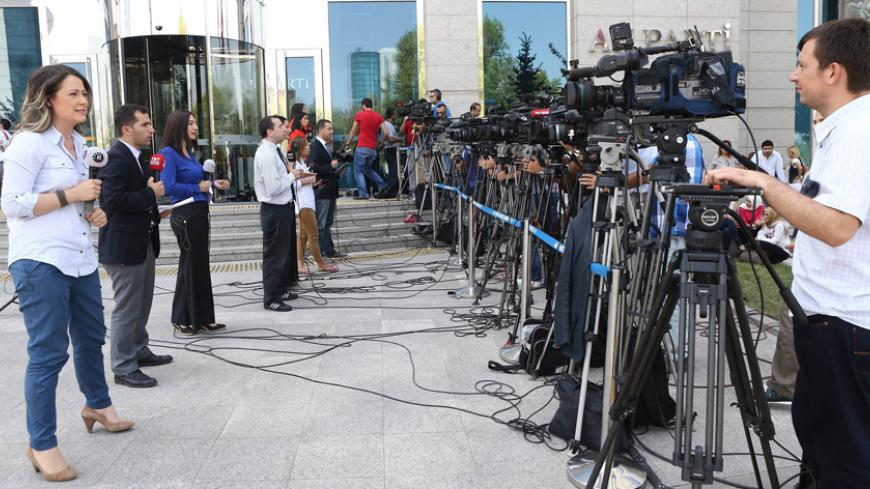 Television journalists report from outside the headquarters of Turkey's ruling Justice and Development Party (AKP) party, shortly before the country's president-elect announces the name of his party's new chairman, in Ankara, on August 21, 2014. Turkey's ruling party is meeting on August 21 to agree on a new leader and prime minister to replace incoming president Recep Tayyip Erdogan, with Foreign Minister Ahmet Davutoglu the frontrunner for the job.AFP PHOTO / ADEM ALTAN        (Photo credit should read AD