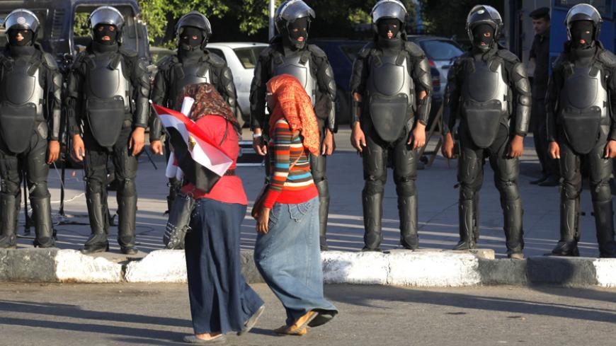 Girls walk past members of the riot police standing guard near a protest against sexual harassment in front of the opera house in Cairo June 14, 2014, after a woman was sexually assaulted by a mob during the June 8 celebrations marking the new president Abdel Fattah al-Sisi's inauguration in Tahrir square. Egypt has asked YouTube to remove a video showing the naked woman with injuries being dragged through the square after being sexually assaulted during the celebrations. Authorities have arrested seven men