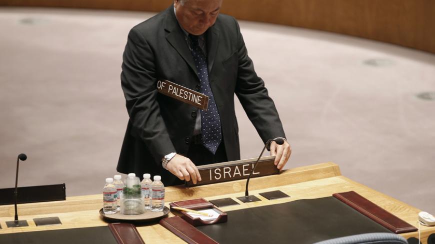 A man places signs for Israel and Palestine at the Council table before a United Nations Security Council meeting on the situation in the Middle East, at U.N. headquarters in New York, July 31, 2014. REUTERS/Mike Segar (UNITED STATES - Tags: POLITICS CIVIL UNREST CONFLICT) - RTR40SYJ