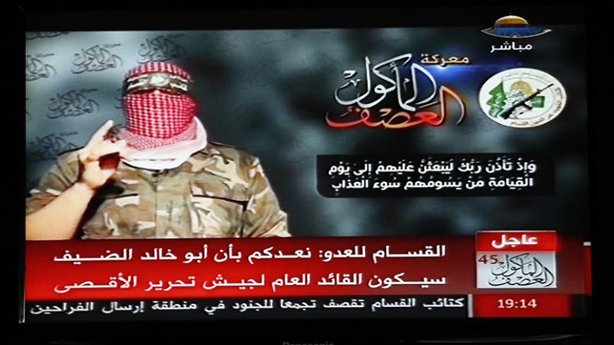 Abu Ubaida, the spokesman of the Izz el-Deen al-Qassam Brigade, the armed wing of the Hamas movement, is pictured on a television screen as he delivers a televised statement on Hamas TV, in Gaza August 20, 2014. Hamas's military wing said on Wednesday an Israeli air strike in Gaza had failed to kill its military commander, Mohammed Deif. In a televised statement, Ubaida said Israel had missed its target. Deif's wife and seven-month-old son were killed in the attack. REUTERS/Suhaib Salem (GAZA - Tags: POLITI