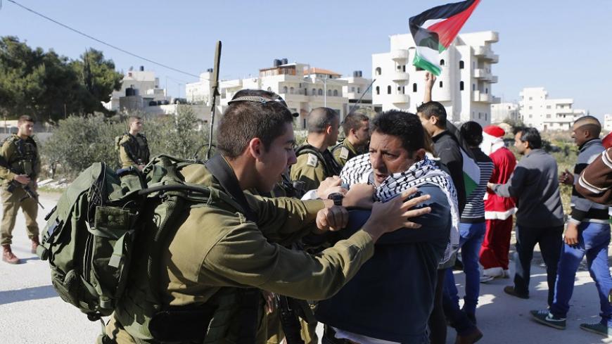 A Palestinian protester scuffles with an Israeli soldier during a protest against Israeli settlements in Maasara village near the West Bank city of Bethlehem December 26, 2014. REUTERS/ Mussa Qawasma (WEST BANK - Tags: POLITICS CIVIL UNREST TPX IMAGES OF THE DAY) - RTR4JAOJ