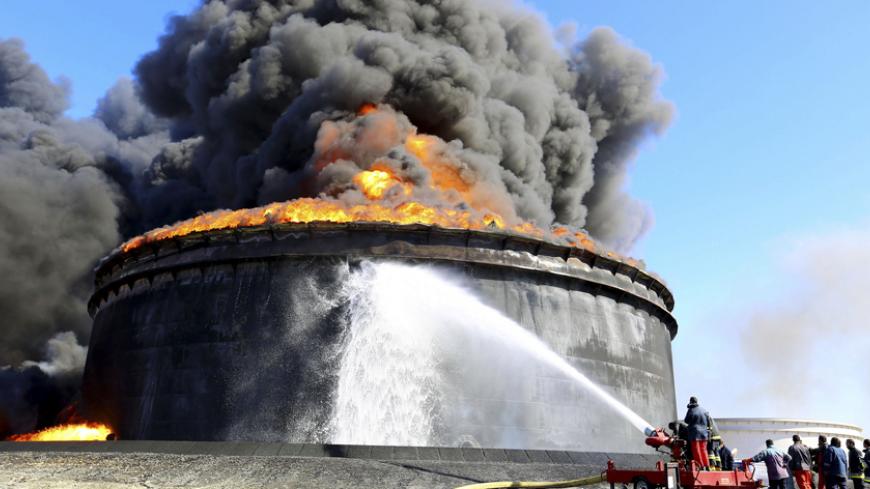 Firefighters work to put out the fire of a storage oil tank at the port of Es Sider in Ras Lanuf December 29, 2014. Oil tanks at Es Sider have been on fire for days after a rocket hit one of them, destroying more than two days of Libyan production, officials said on Sunday. Libya has appealed to Italy, Germany and the United States to send firefighters. REUTERS/Stringer (LIBYA - Tags: CIVIL UNREST POLITICS CONFLICT ENERGY) - RTR4JKBK
