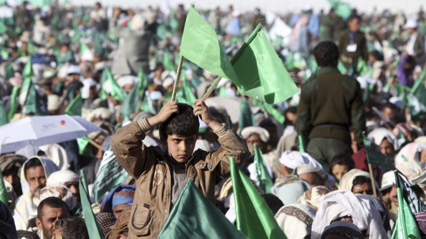 A boy holds up flags of the Shi'ite Houthi movement during a ceremony commemorating the birth of Prophet Mohammed in Sanaa January 3, 2015. REUTERS/Mohamed al-Sayaghi (YEMEN - Tags: RELIGION ANNIVERSARY) - RTR4JYNI