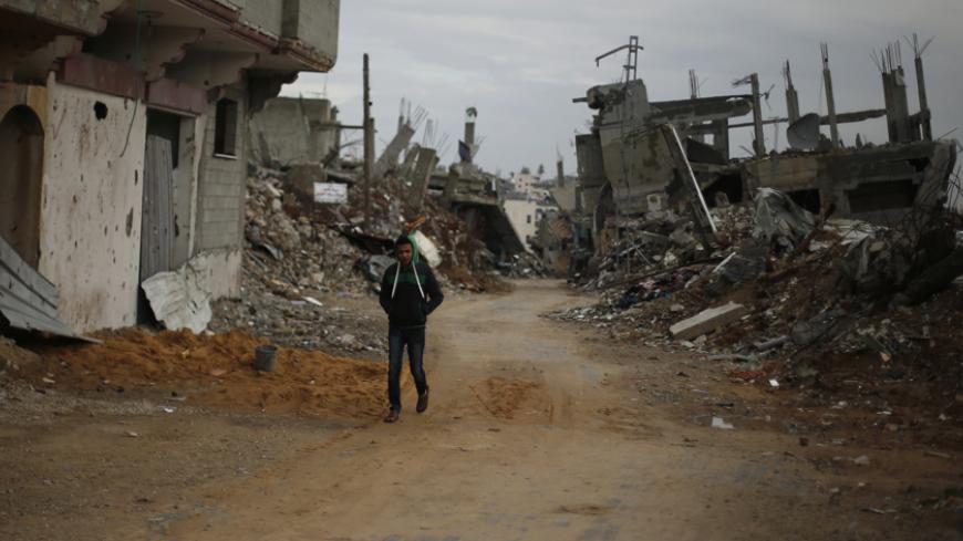 A Palestinian walks near the remains of houses, that witnesses said were destroyed or damaged by Israeli shelling during the July-August war between Israel and Hamas-led Gaza militants, in the east of Gaza City January 4, 2015. REUTERS/Suhaib Salem (GAZA - Tags: POLITICS CIVIL UNREST) - RTR4K02O