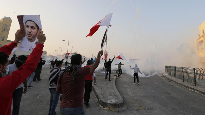 Protesters holding a Bahraini flags and a photo of the leader of Bahrain's main opposition party Al Wefaq, Ali Salman, shout anti-government slogans during clashes in the village of Bilad Al Qadeem south of Manama, January 6, 2015. 
 Bahraini police fired rubber bullets and tear gas to scatter protesters who gathered outside the home of Sheikh Ali Salman, a Shi'ite Muslim opposition leader on Monday, witnesses said, after he was remanded in custody for a further 15 days. Around 100 protesters angry at the d