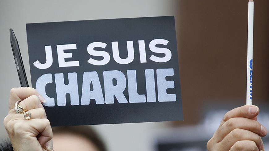 An employee of the Council of Europe holds a placard which read "I am Charlie" and a pen, during a minute of silence in front of the Council of Europe in Strasbourg January 9, 2015, two days after gunmen stormed weekly satirical newspaper Charlie Hebdo in Paris. The two main suspects in the weekly satirical newspaper Charlie Hebdo killings were sighted on Friday in the northern French town of Dammartin-en-Goele where at least one person had been taken hostage, a police source said.    REUTERS/Vincent Kessle