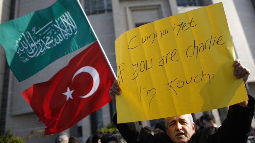A demonstrator holds a banner as others wave Turkish and Islamic flags during a protest against Cumhuriyet, a staunchly secular opposition newspaper, in Istanbul January 15, 2015. Pro-Islamist demonstrators protested against Turkish daily newspaper Cumhuriyet which published a four-page spread of French satirical Charlie Hebdo articles and cartoons on Wednesday. REUTERS/Murad Sezer (TURKEY - Tags: POLITICS CIVIL UNREST CRIME LAW MEDIA) - RTR4LJ1Q