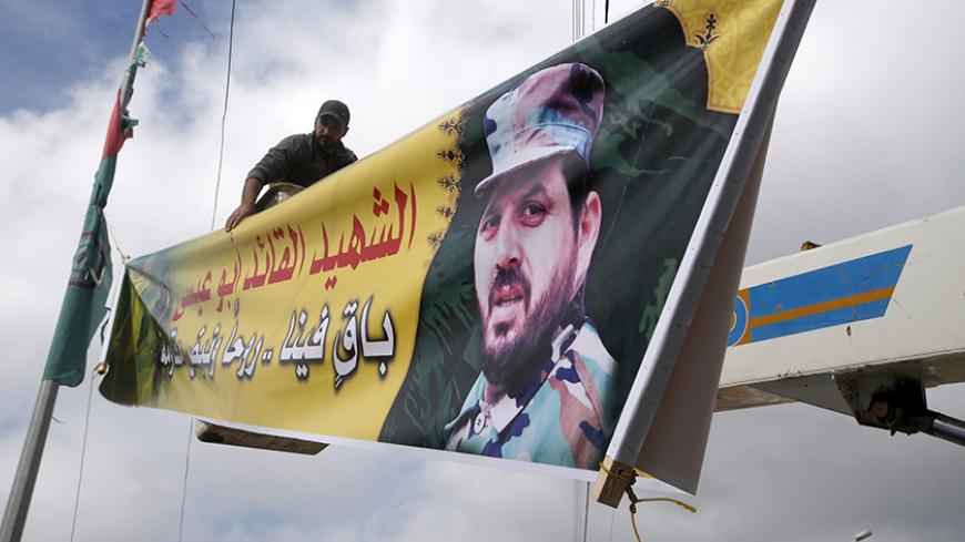 A worker puts up a banner of Lebanon's Hezbollah commander Mohamad Issa, known as Abu Issa, in his hometown of Arab-Salim, south Lebanon January 19, 2015.  Israeli forces took up positions along the disengagement line with Syria on Monday, a day after an Israeli helicopter strike in Syria killed a commander from Lebanon's Hezbollah and the son of the group's late military leader Imad Moughniyah. The missile strike hit a convoy carrying Jihad Moughniyah and Abu Issa, in the province of Quneitra, near the Isr