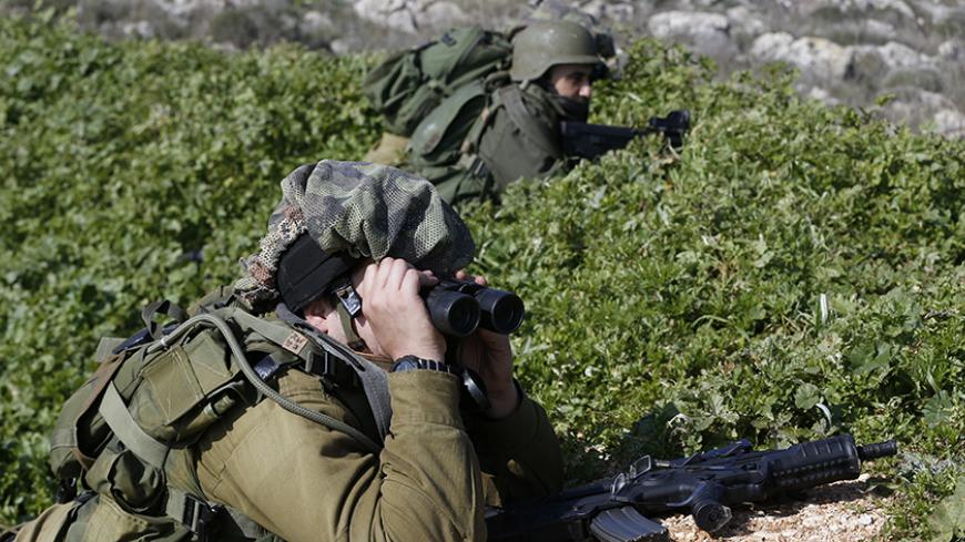 An Israeli soldier looks through binoculars towards the border with Lebanon from above the Israeli town of Metula January 20, 2015. Hezbollah supporters turned out in force on Monday to bury the son of the group's late commander, one of six fighters who died in an Israeli air strike in neighbouring Syria that also killed an Iranian general. Israel has not officially commented on the hit, but an Israeli security source confirmed to Reuters that Israel had carried it out. An Israeli defence official said esca