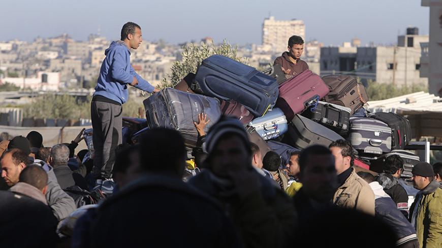 Palestinians load suitcases onto a cart as others, hoping to cross into Egypt, wait for a travel permit at the Rafah crossing between Egypt and the southern Gaza Strip January 21, 2015. Egyptian authorities opened the Rafah border crossing on Tuesday for three days, officials said. Rafah is the only major crossing between impoverished Gaza, home to 1.8 million Palestinians, and the outside world that does not border Israel, which blockades the strip and allows passage mainly on humanitarian grounds. Egypt s