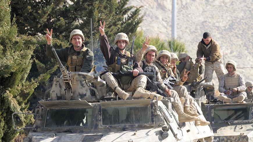 Lebanese soldiers gesture while riding on an armoured vehicle as they leave the mountainous border town of Ras Baalbek January 24, 2015. The Lebanese army said on Saturday three more soldiers were killed in fighting on Friday between troops and militants who attacked an army post near the border with Syria. The army said on Friday it lost five soldiers in an attack near the village of Ras Baalbek in an area that has seen regular incursions by Islamist militants fighting in Syria. REUTERS/Hassan Abdallah (LE