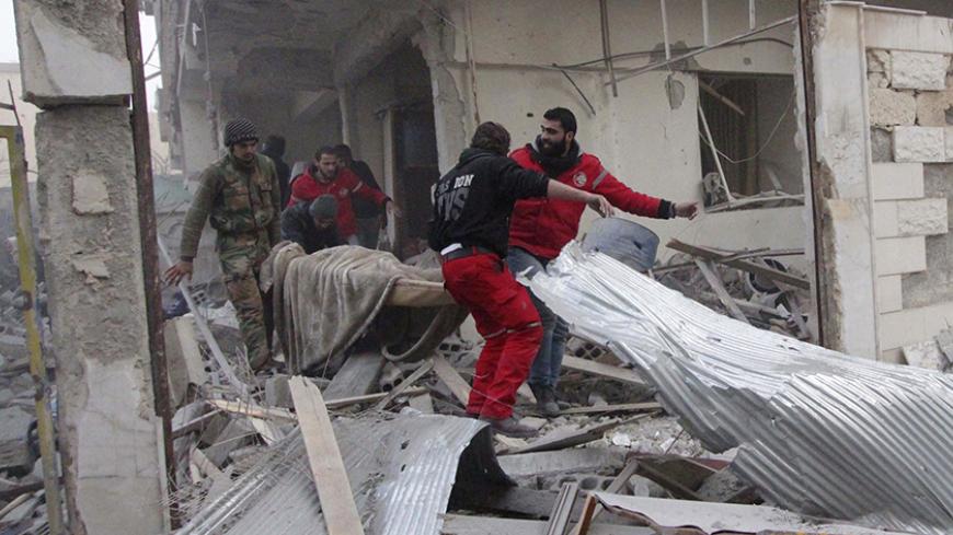 Red Crescent members and residents remove a dead body from a damaged site after what activists said were air strikes by forces loyal to Syria's President Bashar al-Assad in Douma eastern Al-Ghouta, near Damascus January 25, 2015. Islamist fighters struck the Syrian capital with at least 38 rockets on Sunday, killing seven people, a monitoring group said, in one of heaviest attacks on Damascus in over a year. State media confirmed the attack and said at least four people were killed. It said the army was ret