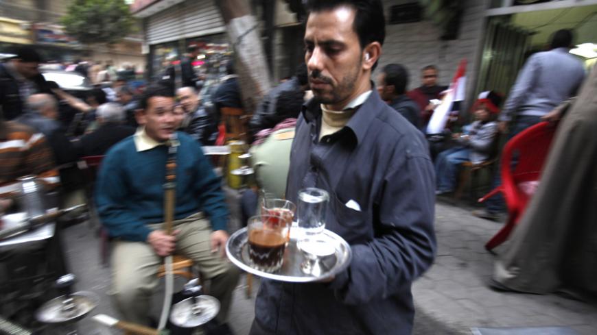 A man delivers coffee in a cafe near Tahrir square in Cairo, February 9, 2011. Egyptians counted the economic cost of more than two weeks of turmoil on Wednesday as re-invigorated protesters flocked again to Cairo's Tahrir Square to demand President Hosni Mubarak quit immediately. REUTERS/Asmaa Waguih (EGYPT - Tags: POLITICS CIVIL UNREST BUSINESS) - RTXXNDD