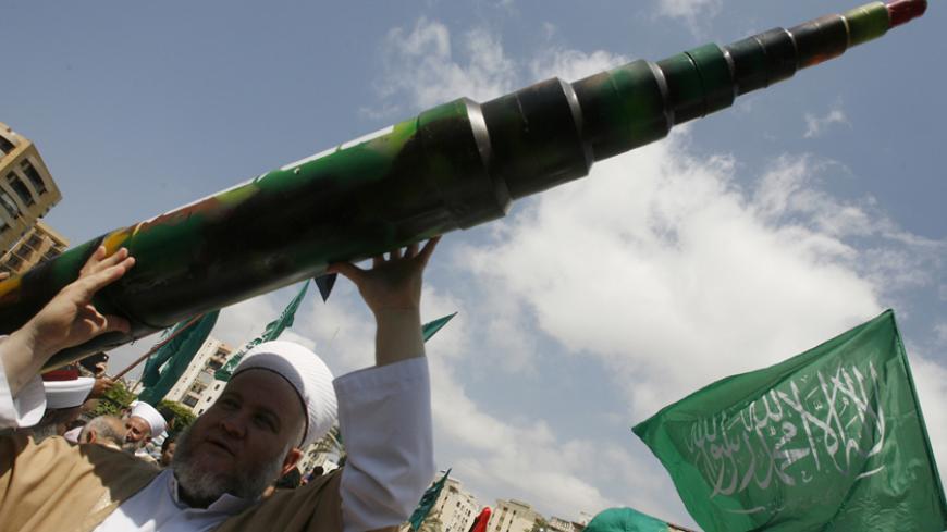 A man holds a mock Qassam rocket during a rally organised by Lebanese and Palestinian supporters of the Islamist movement Hamas and the Islamic Group, Jamaa Islamiya in solidarity with Palestinians in the Gaza strip where Hamas is engaged in a major confrontation with the Israeli army on July 11, 2014 in the southern Lebanese city of Sidon. Two Palestinians were killed in an Israeli strike, raising the toll in four days of violence to 100, Gaza health ministry spokesman Ashraf al-Qudra said. AFP PHOTO / MAH