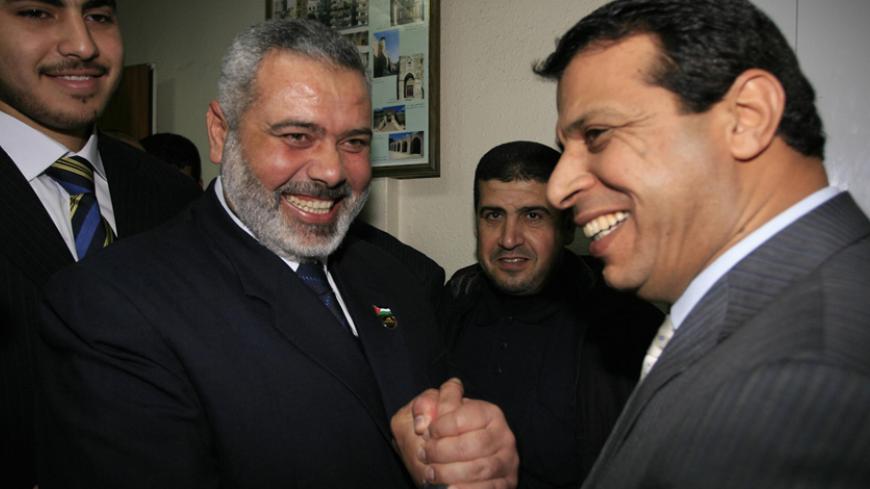 GAZA CITY, -: Palestinian Prime Minister and leader of the Hamas party Ismail Haniya (L) shakes hands with Palestinian Fatah party strongman Mohammed Dahlan, following a vote by MPs approving the long awaited unity government in Gaza City 17 March 2007. The Palestinian parliament today overwhelmingly approved a coalition government uniting the radical Islamist Hamas movement with the secular Fatah of president Mahmud Abbas. Eighty-three members of the 132 member parliament voted in favor of the historic uni