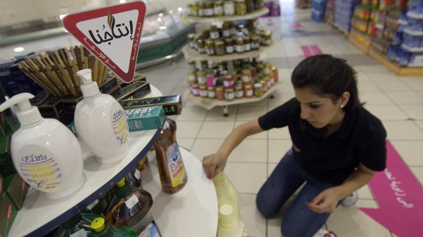 A Palestinian worker sticks Intajuna ("Our Products") stickers on Palestinian goods displayed in a supermarket in the West Bank city of Ramallah August 2, 2009. Intajuna is one of many campaigns asking Palestinians to avoid Israeli products. After 40 years of occupation, the Palestinian economy is tied to Israel's, so attempts to reduce its dependence clash with hard realities. Picture taken August 2, 2009. To match feature PALESTINIANS-ISRAEL/BOYCOTT REUTERS/Fadi Arouri (WEST BANK POLITICS BUSINESS) - RTR2
