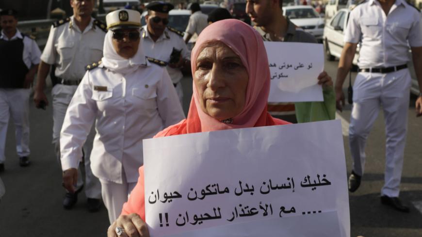 A female protester holds a sign, near police officers as she joins others protesting against sexual harassment after a woman was sexually assaulted by a mob during Sunday's celebrations, marking the new president's inauguration in Tahrir square, in Cairo June 11, 2014. Egyptian authorities have arrested seven men for sexually harassing women near Cairo's Tahrir Square while thousands celebrated the inauguration of Sisi, the Interior Ministry said on Monday. A video posted on YouTube on Sunday, claiming to d
