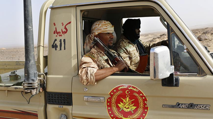 A Libyan army vehicle patrols on a desert road between Libya and Algeria May 29, 2014. Libya's southwestern tip in the Sahara bordering Algeria and Niger has turned into an open door for illegal migrants from sub-Saharan countries heading for Europe, with the chaotic government in Tripoli appearing to have abandoned all control. The revolt that overthrew Libyan leader Muammar Gaddafi three years ago emptied Libya's arsenals, flooded the region with guns and dismantled much of the state apparatus, giving wel