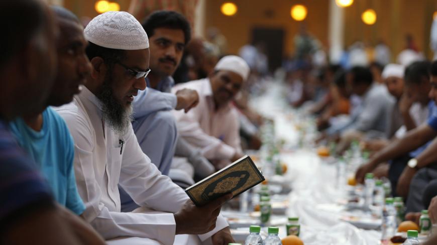 A Muslim man reads the Koran as others gather to have their Iftar meal on the first day of the holy fasting month of Ramadan at Prince Turki bin Abdullah mosque in Riyadh June 29, 2014.  REUTERS/Faisal Al Nasser (SAUDI ARABIA - Tags: RELIGION FOOD) - RTR3WBHJ