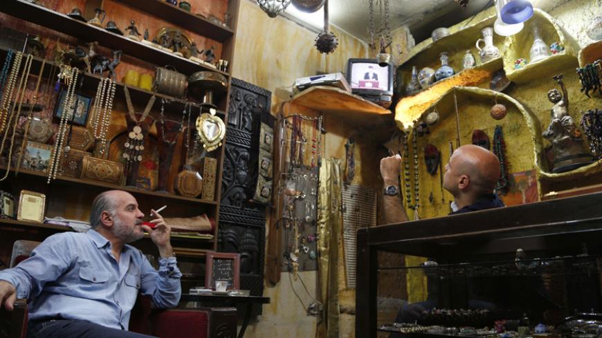 People sit in a shop as they watch TV broadcasting Syria's President Bashar al-Assad speaking as he is sworn in for a new seven-year term, in Damascus July 16, 2014. Al-Assad, who was sworn in for a new term on Wednesday, said Western and Arab states that have supported "terrorism" will pay a "high price" and that he would fight insurgents until security was restored to the whole country.
 REUTERS/Omar Sanadiki (SYRIA - Tags: POLITICS CIVIL UNREST) - RTR3YVXN