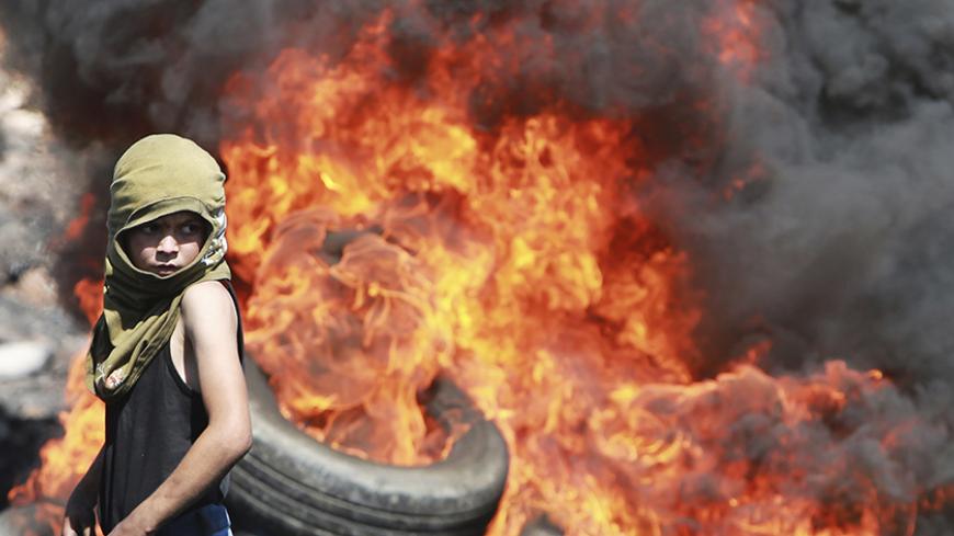 A Palestinian boy looks on near burning tyres during cashes with Israeli soldiers following a protest against the near-by Jewish settlement of Qadomem, in the West Bank village of Kofr Qadom near Nablus September 19, 2014. REUTERS/Abed Omar Qusini (WEST BANK  - Tags: POLITICS CIVIL UNREST CONFLICT TPX IMAGES OF THE DAY) - RTR46XNM