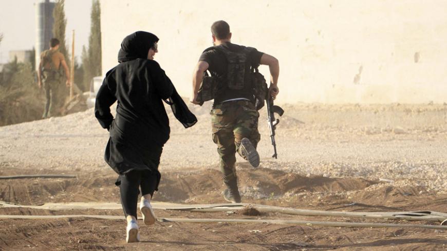 A woman reporter runs with a rebel fighter to avoid snipers at the frontline against the Islamic State fighters in Aleppo's northern countryside October 10, 2014. REUTERS/Jalal Al-Mamo (SYRIA - Tags: POLITICS CIVIL UNREST) - RTR49POS