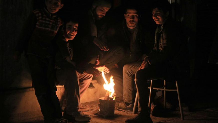 Residents warm themselves by a fire on New Year's Eve in eastern al-Ghouta, near Damascus December 31, 2014. Residents have been facing an electricity blackout for 2 years, activists said. Picture taken December 31, 2014. REUTERS/Bassam Khabieh (SYRIA - Tags: SOCIETY) - RTR4JSA6