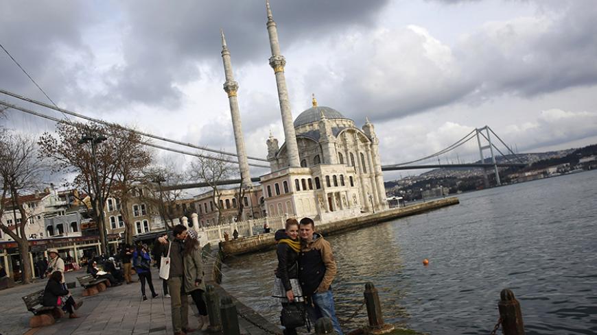 Couples pose for souvenir pictures in front of the Ottoman-era Ortakoy Mecidiye mosque by the Bosphorus strait in Istanbul January 5, 2015.  REUTERS/Murad Sezer (TURKEY - Tags: RELIGION CITYSCAPE TRAVEL SOCIETY) - RTR4K534