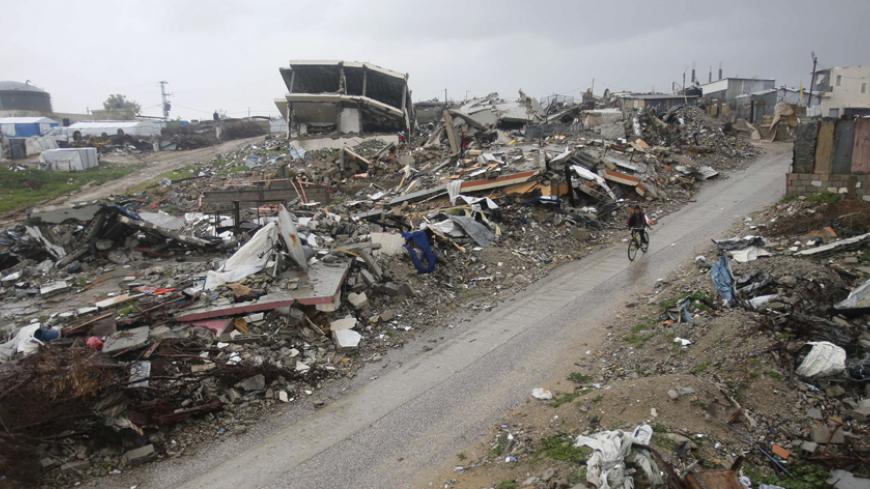 A Palestinian boy rides a bicycle past the ruins of houses that witnesses said were destroyed by Israeli shelling during a 50-day war last summer, on a rainy day in the village of Johar a-Deek near central Gaza Strip January 9, 2015. Heavy rains and near-freezing temperatures in the approaching storm threatened to deepen the misery in the Gaza Strip, where streets are still strewn with wreckage from a 50-day war with Israel last summer, thousands live in U.N. shelters and damaged homes and the power is on o