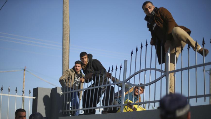 Palestinians, hoping to cross into Egypt, climb a wall as policemen loyal to Hamas stand guard at the Rafah crossing between Egypt and the southern Gaza Strip January 20, 2015. Egyptian authorities opened Rafah crossing, Gaza's main window to the outside world, on Tuesday for three days, officials said. Egypt shut the crossing over violence with Islamist militants in Egypt's adjacent Sinai region last October. Since then, it opened the crossing partially and on a few occasions to allow thousands of Palestin