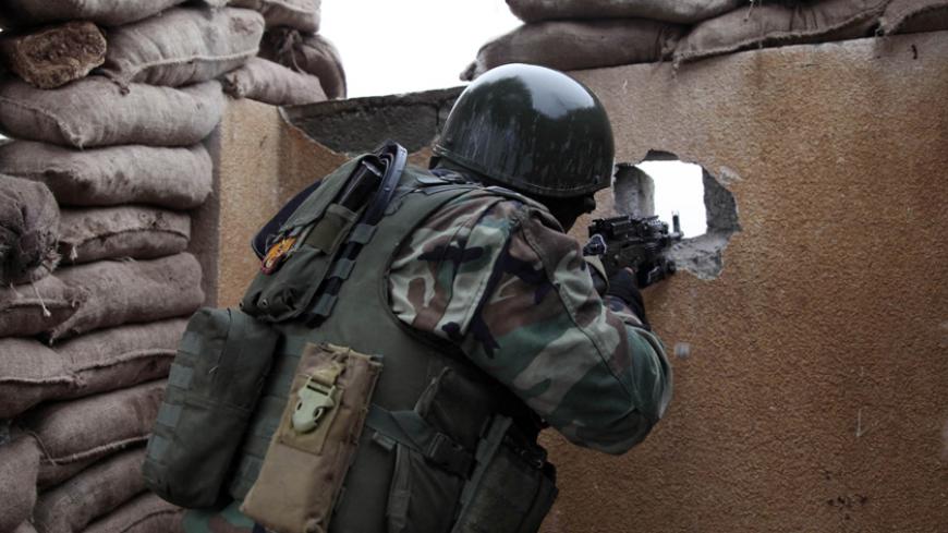 A Kurdish Peshmerga fighter aims his weapon through a hole in a wall on the front line of fighting against Islamic State militants in the outskirts of Mosul January 30, 2015.  REUTERS/Ari Jalal (IRAQ - Tags: CIVIL UNREST) - RTR4NNTG