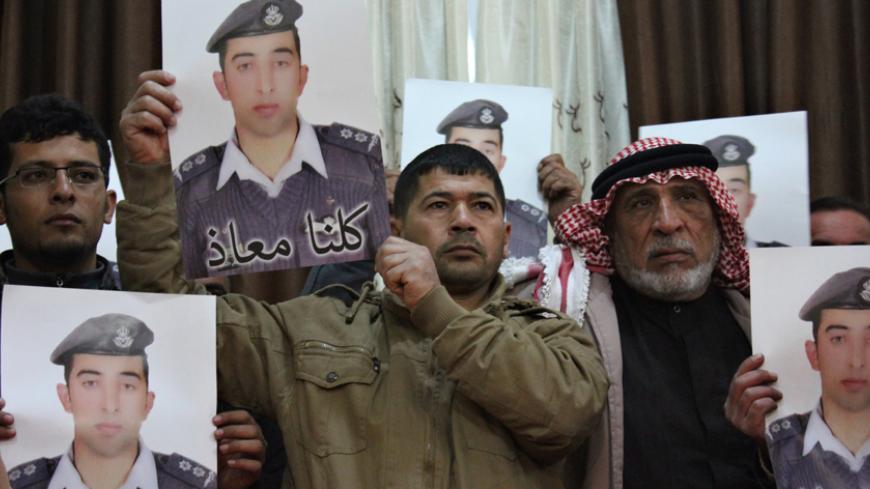 Relatives of Islamic State captive Jordanian pilot Muath al-Kasaesbeh hold his poster as they take part in a rally in his support at the family's headquarters in the city of Karak, January 31, 2015. The words on the portrait reads, "We are all Muath." REUTERS/Stringer (JORDAN - Tags: POLITICS CIVIL UNREST TPX IMAGES OF THE DAY) - RTR4NQMF