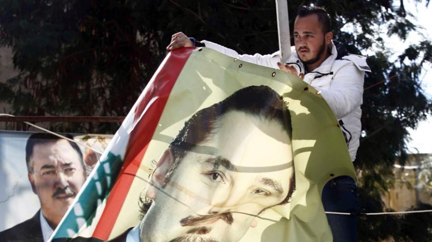 Men take down a picture of former Lebanese Prime Minister Saad al-Hariri in the mainly Sunni Beirut neighbourhood of Tariq al-Jadideh February 5, 2015. Lebanon has begun removing political posters and party banners from neighbourhoods of the capital in a move to unify a country still divided from a civil war, following an agreement between the militant and political Hezbollah party and its rivals. Picture taken February 5, 2015. REUTERS/Mohamed Azakir (LEBANON - Tags: POLITICS SOCIETY) - RTR4OHK4