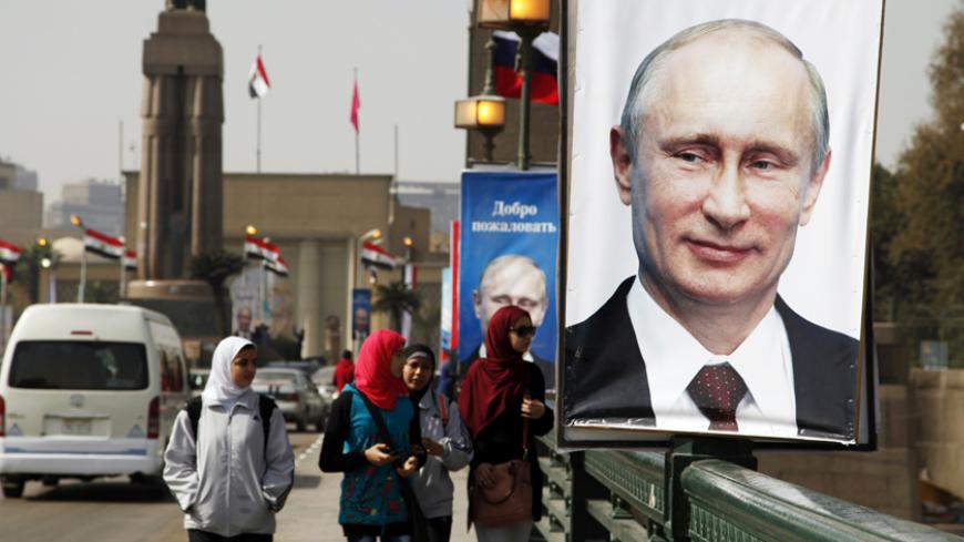 Girls walk past a banner with a picture of Russian President Vladimir Putin along a bridge, in central Cairo February 9, 2015. Putin is due to arrive on Monday on his first visit to Egypt in ten years. REUTERS/Asmaa Waguih(EGYPT - Tags: POLITICS) - RTR4OTY2