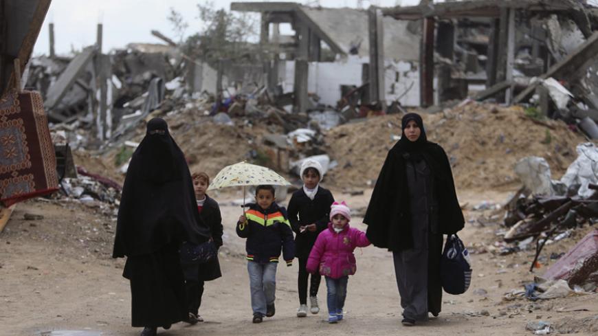 Palestinians walk near the ruins of houses that witnesses said were destroyed or damaged by Israeli shelling during a 50-day war last summer, on a winter day east of Gaza City February 20, 2015. REUTERS/Ibraheem Abu Mustafa (GAZA - Tags: POLITICS CIVIL UNREST ENVIRONMENT SOCIETY) - RTR4QE85