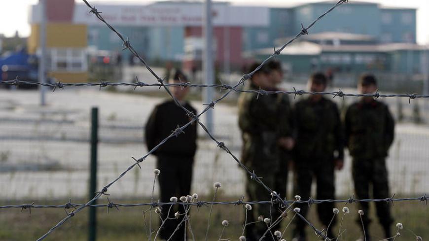 Gendarme officers watch demonstrators from inside the perimeter of the heavily guarded Silivri prison where the trial of a shadowy-right wing group took place, 70km (43 miles) west of Istanbul, October 20, 2008. Ergenekon, a shadowy right-wing group, went on trial in Turkey on Monday on charges of trying to topple Prime Minister Tayyip Erdogan's government. Eighty-six people, including retired army officers, politicians, lawyers and journalists, are accused of planning assassinations and bombings to sow cha