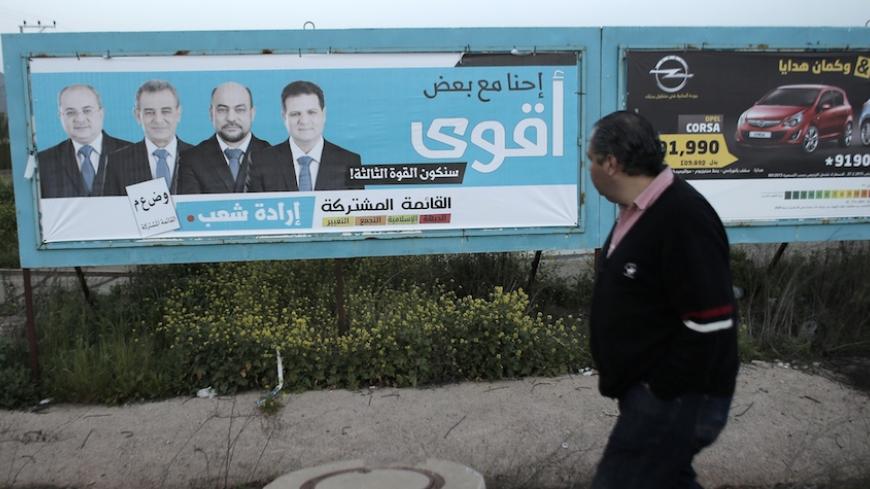 An Israeli Arab walks past a campaign poster showing Israeli-Arab candidates who are members of a joint list of Arab parties (from L to R), Ahmad Tibi, Jamal Zahalka, Masud Ghanayem and Ayman Odeh, in Kfar Menda, 16 kilometres northwest of the city of Nazareth, on March 8, 2015. General elections in Israel are to take place on March 17. AFP PHOTO / AHMAD GHARABLI        (Photo credit should read AHMAD GHARABLI/AFP/Getty Images)