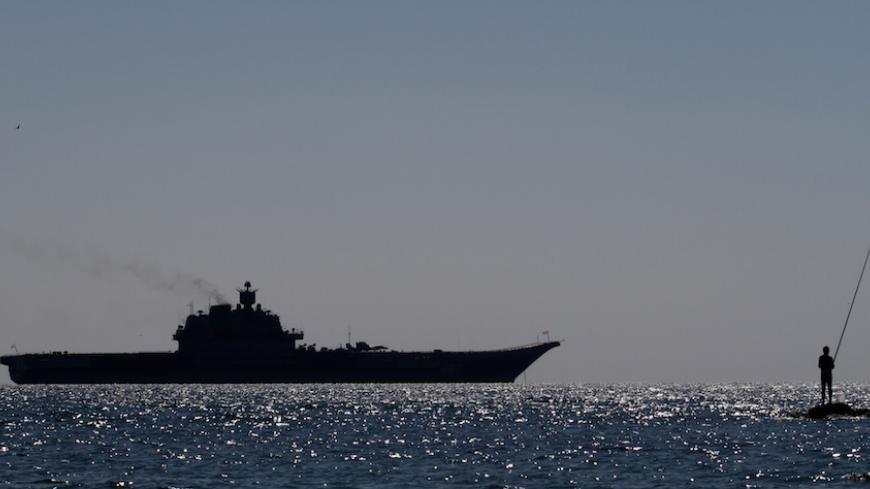 A man fishes in front of the Russian Navy Kuznetsov class aircraft carrier moored off the coast of the town of Limassol, in the Mediterranean island of Cyprus on February 27, 2014. AFP PHOTO / YIANNIS KOURTOGLOU        (Photo credit should read Yiannis Kourtoglou/AFP/Getty Images)