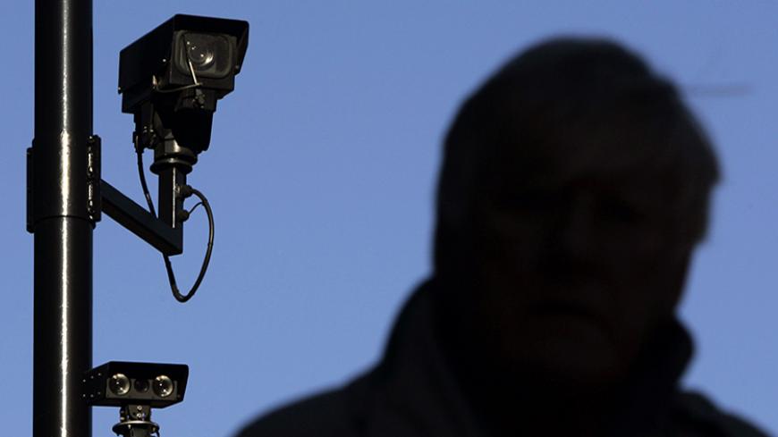 A security camera overlooks a man as he walks down a street in London November 2, 2006. Britain is becoming a surveillance society where individuals are filmed hundreds of times a day by CCTV and where companies "data mine" to build up profiles on customers, the Information Commissioner warned on Thursday.  REUTERS/Luke MacGregor (BRITAIN) - RTR1IXR5