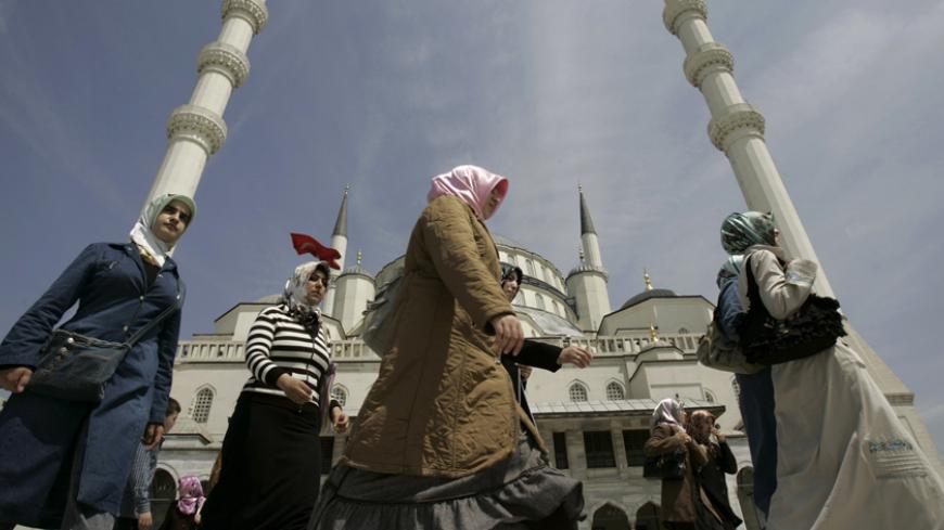 Women walk past a mosque in Ankara April 22, 2007. The women at a protest in Istanbul's old quarter want to wear their headscarves in school, university and parliament, but Muslim Turkey's secular system forbids that, with laws pious Muslims see as a breach of their personal and religious freedom. The Islamist-rooted ruling AK Party says it wants to lift the ban, a key demand of its grass-root supporters, but has faced fierce opposition from Turkey's powerful secular elite.  Picture taken on April 22, 2007.