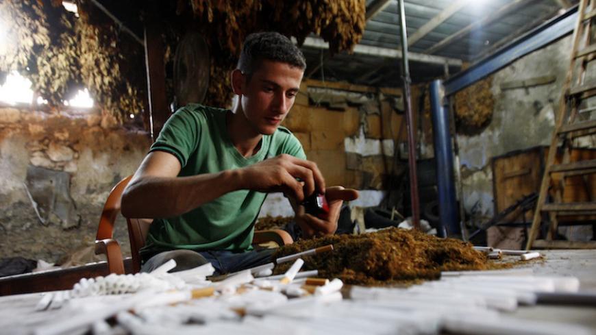 A Palestinian worker fills up empty cigarettes manually with locally grown tobacco in a small factory in the town of Ya'bad near the West Bank city of Jenin October 8, 2012. REUTERS/Abed Omar Qusini (WEST BANK - Tags: SOCIETY HEALTH) - RTR38XLE
