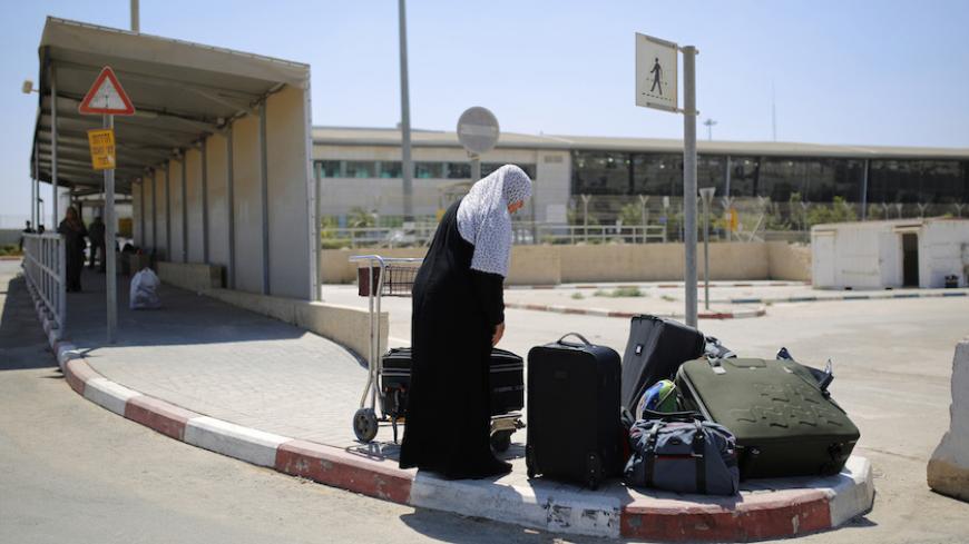 A Palestinian woman loads her suitcases onto a luggage cart before crossing into Gaza through Israel's Erez crossing August 6, 2014.  A Gaza truce was holding on Wednesday as Egyptian mediators pursued talks with Israeli and Palestinian representatives on an enduring end to a war that has devastated the Hamas Islamist- dominated enclave. Israel withdrew ground forces from the Gaza Strip on Tuesday morning and started a 72-hour Egyptian-brokered ceasefire with Hamas as a first step towards a long-term deal. 