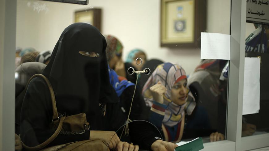 Palestinian Hamas-hired civil servants wait to receive payment at a post office in Gaza City October 29, 2014. Some 24,000 civil servants hired by the Islamist group Hamas, many of whom have not received a full salary in almost a year, finally got some pay on Wednesday from the new Palestinian unity government based in the West Bank. The funds were supplied by the gas-rich kingdom of Qatar, which is an ally of Hamas. But the fact the cash was delivered by the West Bank administration gave a boost to hopes t