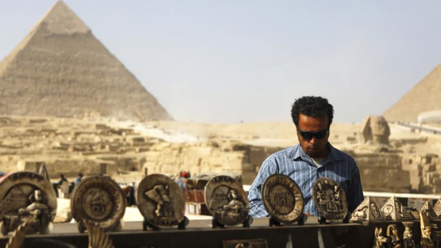 A souvenirs vendor waits for tourists in front of the Sphinx and the Giza Pyramids on the outskirts of Cairo, December 9, 2014.  Egypt's tourism revenues jumped 112 percent to about $2 billion in the third quarter of 2014, a tourism ministry official said, suggesting the key industry was showing signs of recovery, albeit from a particularly bad third quarter last year. Tourism, an important source of foreign currency, has been hammered since the popular uprising that toppled Hosni Mubarak in 2011.   REUTERS