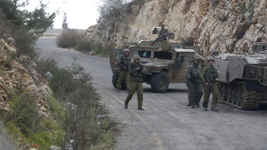 Israeli soldiers walk near military vehicles near Israel's border with Lebanon January 28, 2015. At least 22 shells fired from Israel hit open farmland in southern Lebanon close to the frontier, a Lebanese security source in the area said on Wednesday. Earlier in the day an anti-tank missile was fired at an Israeli military vehicle near the frontier with Lebanon, an Israeli army spokesman said.   REUTERS/Baz Ratner (ISRAEL - Tags: MILITARY POLITICS CIVIL UNREST) - RTR4NA14