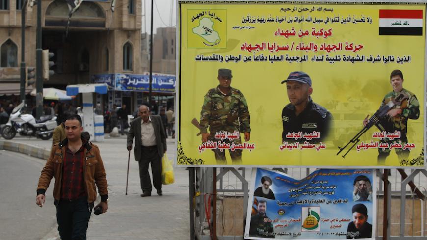 A man walks past a poster, commemorating Shi'ite fighters who were killed in battles with Islamic State militants, at Tahrir Square in Baghdad February 7, 2015. Baghdad residents commended a decision by Iraq's Prime Minister Haider al-Abadi to end their city's nightime curfew on Saturday. Some form of curfew has been in place since the U.S.-led invasion to topple Saddam Hussein in 2003, hindering commercial and civilian movement. The midnight (2100 GMT) to 5 a.m. curfew has been in place for more than seven
