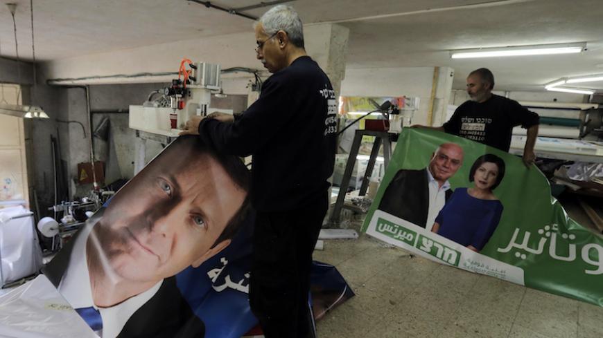 Workers hold freshly printed campaign banners in Arabic that depict Isaac Herzog (L), who heads the centre-left Zionist Union alliance with former cabinet minister Tzipi Livni, and Zehava Galon (R), chair of the left-wing Meretz party, at a printing factory in the Arab village of Baqa al-Gharbiya in northern Israel March 2, 2015. Opinions polls show a tight race ahead of the March 17 election, campaigning for which has been dominated by economic issues like high living costs and workers wages. REUTERS/Ammar