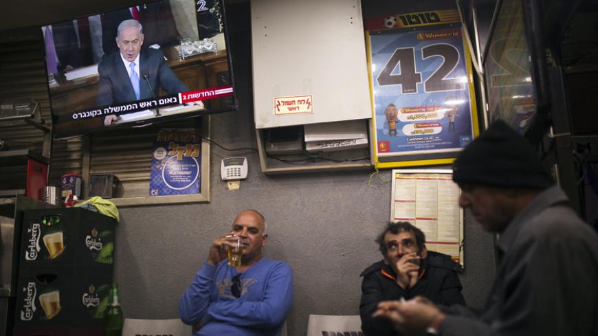 People sit under a television broadcasting Israel's Prime Minister Benjamin Netanyahu's speech to the U.S. Congress, at a kiosk in the southern city of Ashkelon March 3, 2015. Netanyahu warned U.S. President Barack Obama on Tuesday against accepting a nuclear deal with Iran that would be a "countdown to a potential nuclear nightmare" by a country that "will always be an enemy of America". REUTERS/Amir Cohen (ISRAEL - Tags: POLITICS) - RTR4RWZN