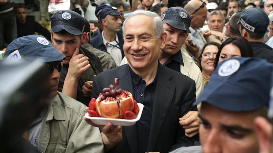 Israel's Prime Minister Benjamin Netanyahu (C) holds a plate of fruit during a visit to Mahane Yehuda fruit and vegetable market in Jerusalem March 9, 2015. Israelis will vote in a parliamentary election on March 17, choosing among party lists of candidates to serve in the 120-seat Knesset. Currently, polls show Netanyahu's Likud party and the centre-left Zionist Union opposition running neck-and-neck, with each predicted to win around 24 seats in the Knesset. REUTERS/Noam Moskowitz (JERUSALEM - Tags: POLIT