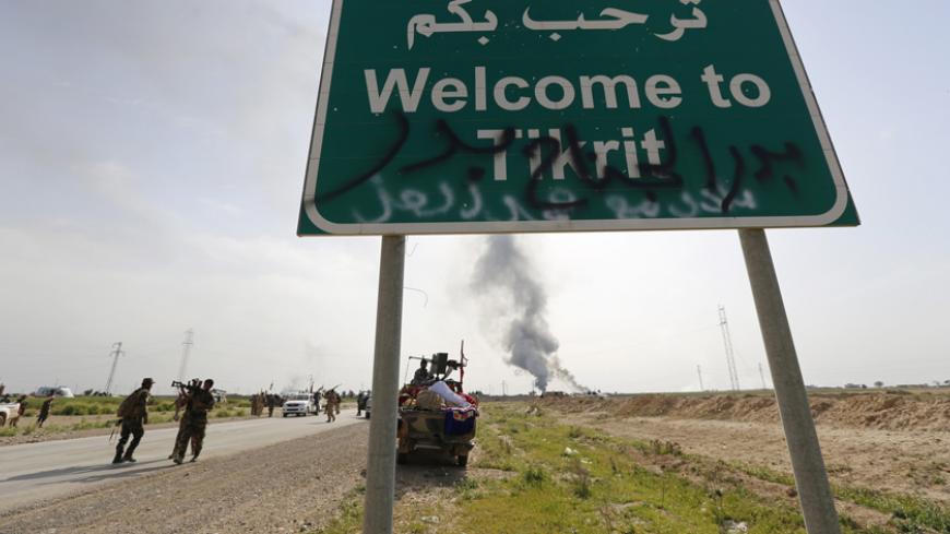 A billboard is seen as smoke rises from a clash with Islamic State militants in the town of al-Alam March 9, 2015. Just north of Tikrit, home city of executed Sunni former president Saddam Hussein, Iraqi security forces and Shi?ite militia fighters began an offensive to regain control over the town of al-Alam.   REUTERS/Thaier Al-Sudani (IRAQ - Tags: POLITICS CIVIL UNREST CONFLICT) - RTR4SNWP